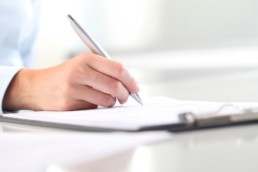 Woman's hands writing on sheet of paper in a clipboard and a pen © visivasnc / Fotolia